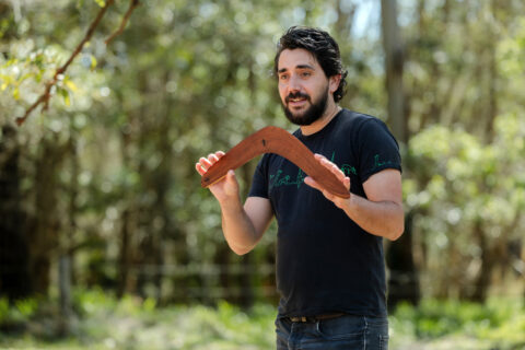 A man standing holding a Duuwa (boomerang)